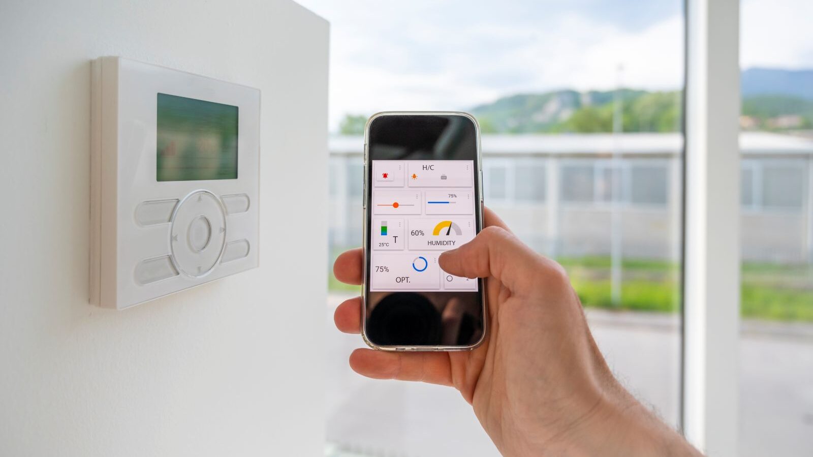 Hand steuert Smart-Home-System zur Optimierung von Heizung und Klimaanlage über eine Smartphone-App, die Temperatur (25°C) und Luftfeuchtigkeit (60%) anzeigt – Energieeffizienz.
