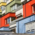 Modernes Mehrfamilienhaus mit farbig gestalteter Fassade in Rot, Gelb, Grün und Blau mit Balkonen und Rollläden