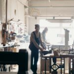 Handwerker in einer hellen Schreinerwerkstatt arbeiten an Holzprojekten an Werkbänken mit Maschinen und Werkzeugen