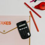 Taschenrechner, rote Stifte und Klebeband neben Steuerformular zur Berechnung von Grundsteuer und Neubewertung