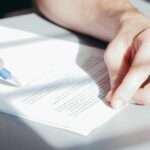 Handwerker unterzeichnet Vertrag oder Gewährleistungsdokument mit Kugelschreiber bei Sanierungsauftrag