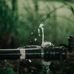 Wasserleck an Gartenschlauch-Anschluss mit spritzendem Wasser und Wassertropfen