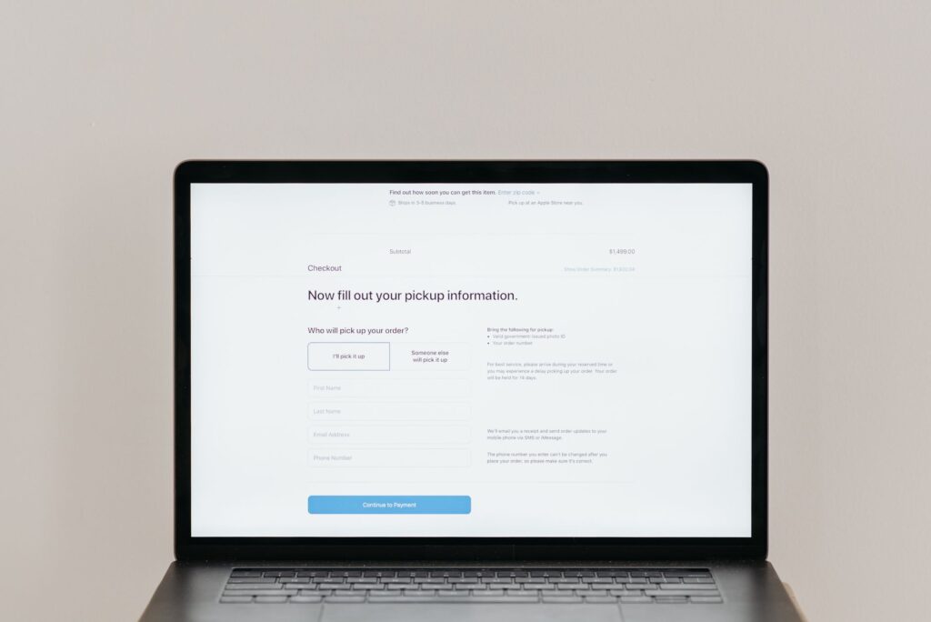 Laptop zeigt Online-Checkout-Formular mit Abholmöglichkeiten und Eingabefeldern für persönliche Daten zur Bestellung