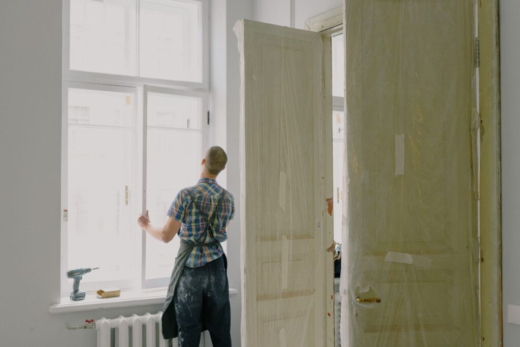 Handwerker beim Einbau einer neuen Türzarge in renoviertem Raum mit weißen Fensterrahmen