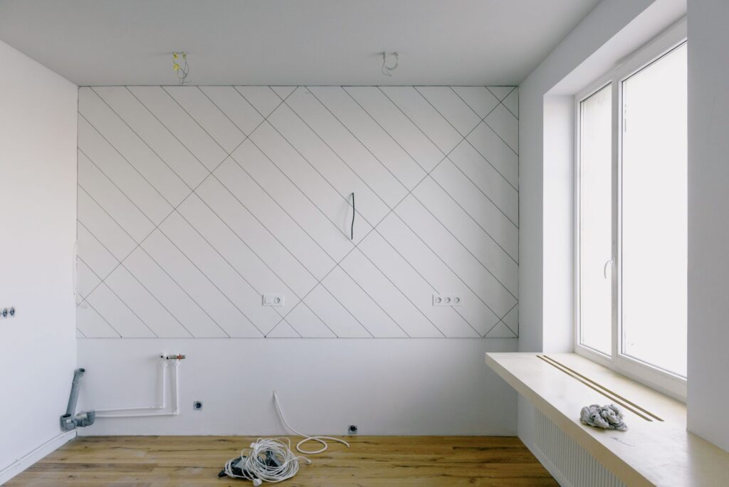 Renovierungsraum mit Gipskartonwand im Rautenmuster, Elektroinstallationen und Leitungen während der Sanierung